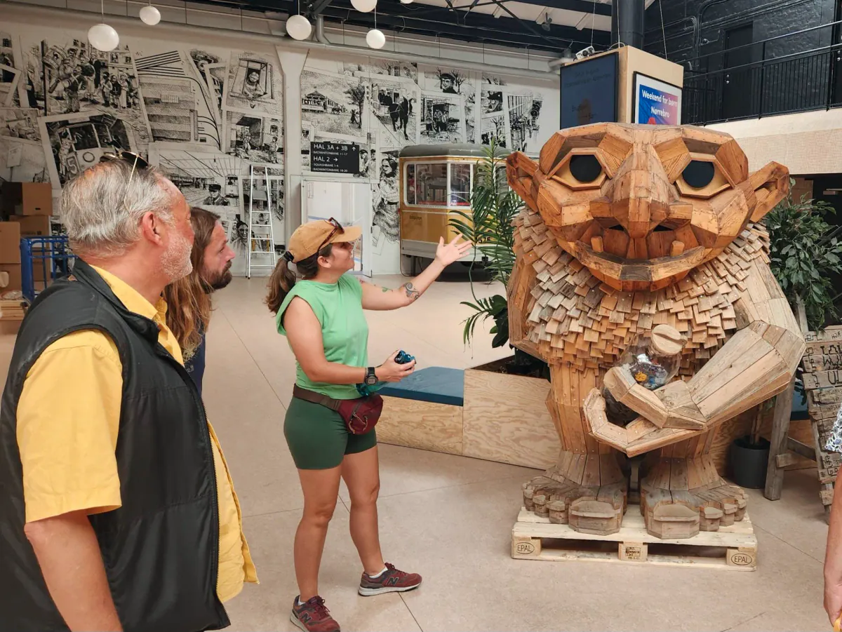 Guests and their host by a wooden troll by the artist Thomas Dambo